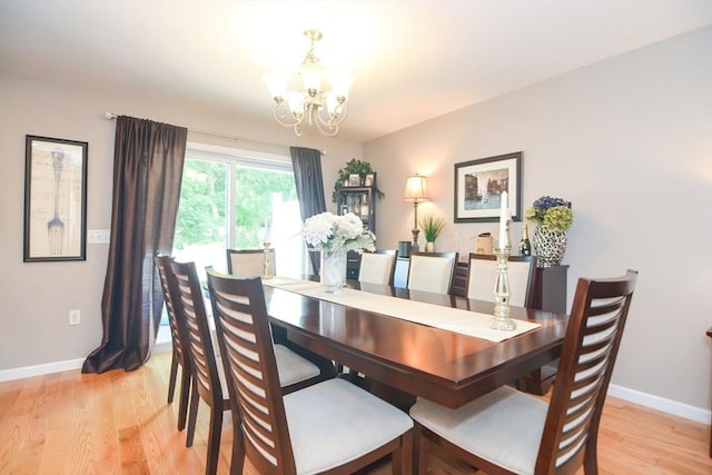 dining area featuring light wood-type flooring, baseboards, and a chandelier