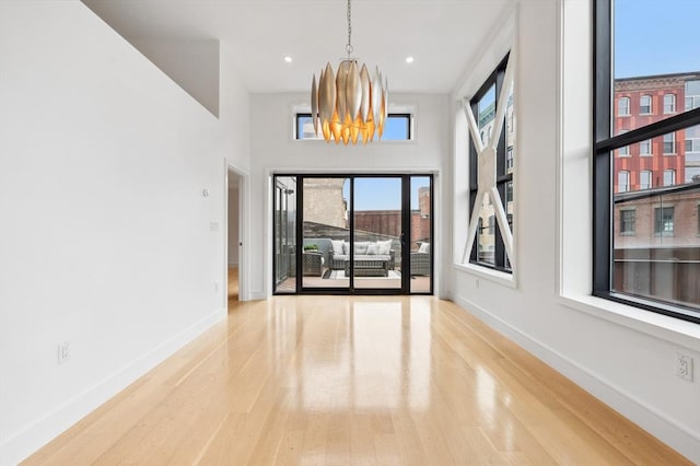 spare room featuring wood-type flooring, a wealth of natural light, and a notable chandelier