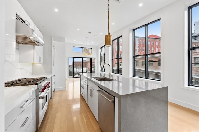 kitchen with sink, appliances with stainless steel finishes, white cabinetry, hanging light fixtures, and a spacious island