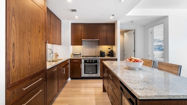 kitchen featuring light hardwood / wood-style floors, a kitchen island, appliances with stainless steel finishes, sink, and tasteful backsplash