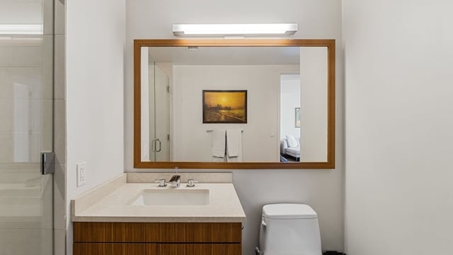 bathroom with vanity with extensive cabinet space, toilet, and a shower with door