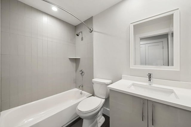 full bathroom featuring vanity, tiled shower / bath combo, and toilet