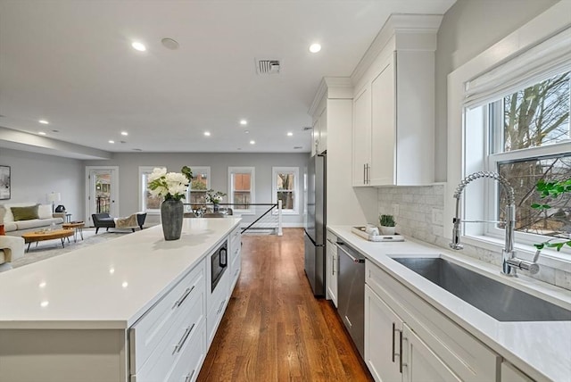 kitchen featuring dark hardwood / wood-style floors, sink, white cabinets, decorative backsplash, and stainless steel appliances