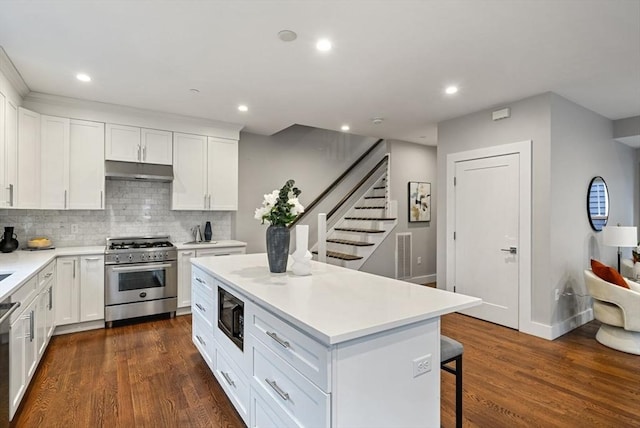 kitchen with tasteful backsplash, white cabinetry, appliances with stainless steel finishes, and a center island