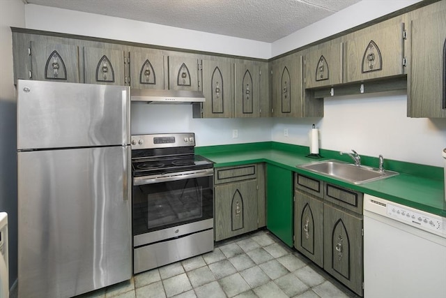 kitchen featuring a textured ceiling, under cabinet range hood, a sink, appliances with stainless steel finishes, and dark countertops