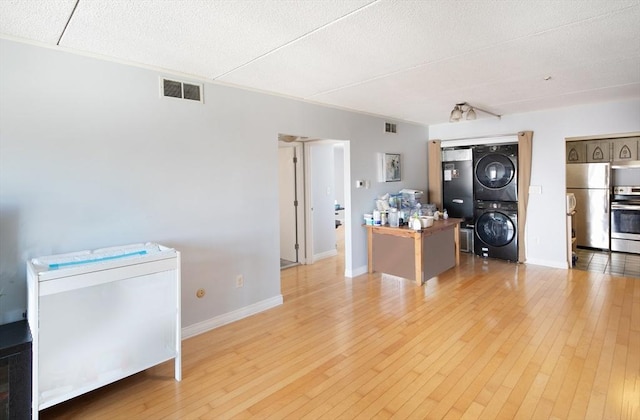 interior space with stainless steel appliances, stacked washer / drying machine, light wood-type flooring, and visible vents