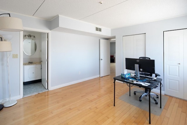 office featuring ornamental molding, visible vents, a textured ceiling, and wood finished floors