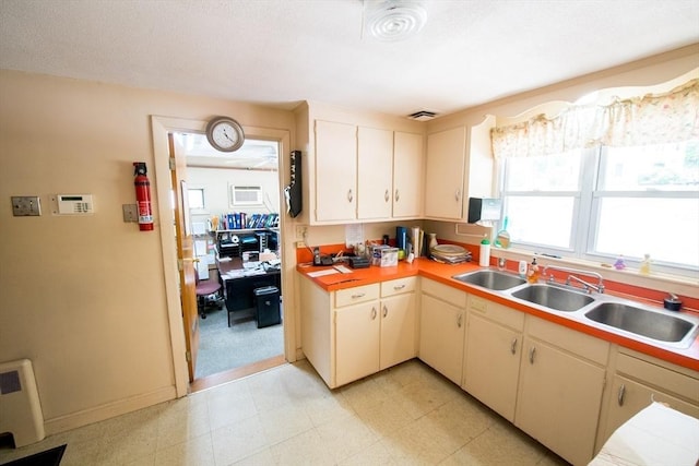 kitchen featuring light countertops, a sink, and an AC wall unit