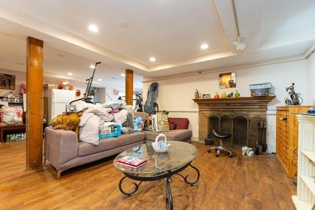 living area featuring recessed lighting, a raised ceiling, a fireplace, and wood finished floors