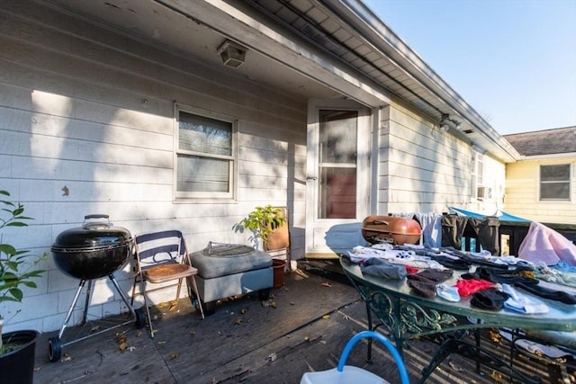 wooden deck featuring outdoor dining area, a grill, and a patio