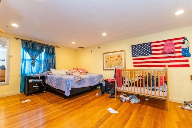 bedroom with baseboards, wood finished floors, and recessed lighting