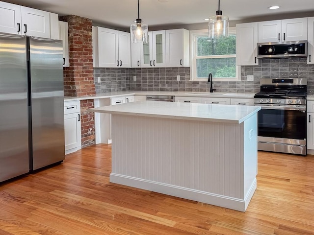 624 Western Ave, Gloucester, MA 01930 - kitchen with stainless steel appliances, light wood finished floors, white cabinetry, and hanging light fixtures