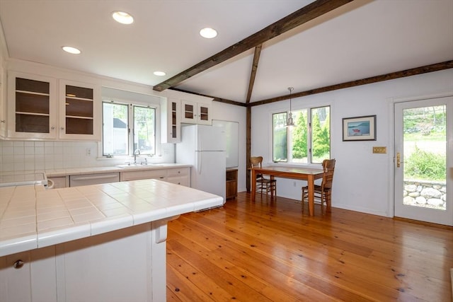 kitchen with a sink, white appliances, decorative backsplash, tile counters, and white cabinets