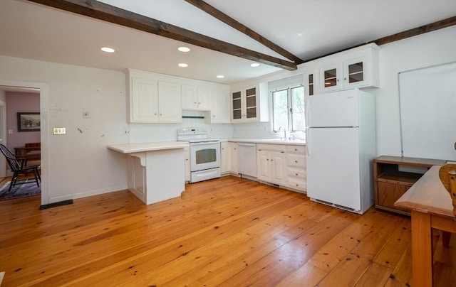 kitchen with a sink, a peninsula, white appliances, light countertops, and light wood-style floors