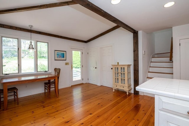 entrance foyer with light wood-style flooring, baseboards, visible vents, stairway, and vaulted ceiling with beams