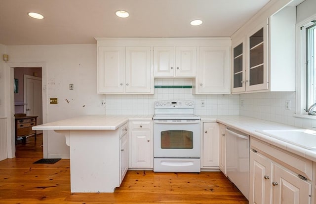 kitchen with a peninsula, dishwashing machine, a sink, electric range, and white cabinets