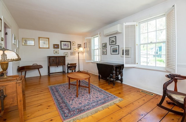 sitting room with light wood finished floors, an AC wall unit, and visible vents