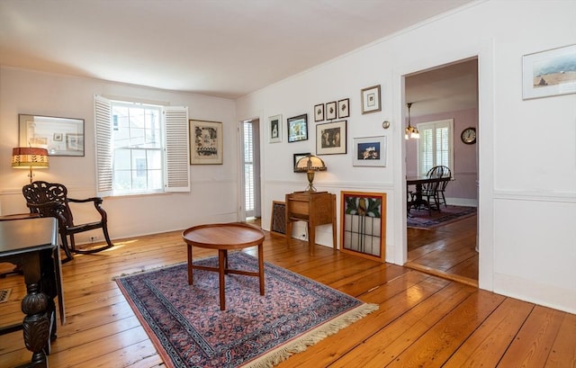 living area with crown molding and wood-type flooring