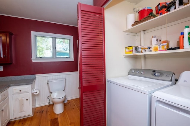 washroom with washing machine and dryer, light wood-style flooring, a wainscoted wall, and laundry area