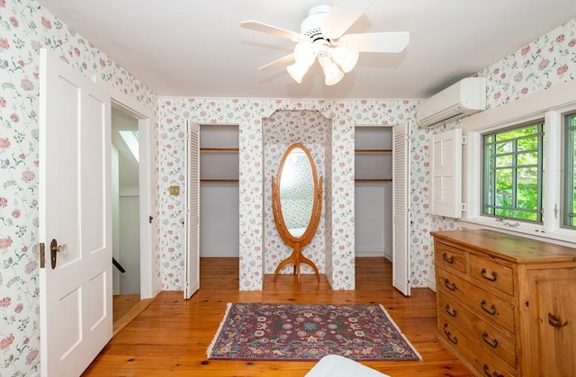 entryway featuring a wall mounted air conditioner, wallpapered walls, and light wood-style floors
