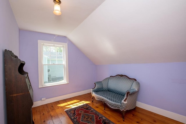 living area with vaulted ceiling, hardwood / wood-style flooring, and baseboards