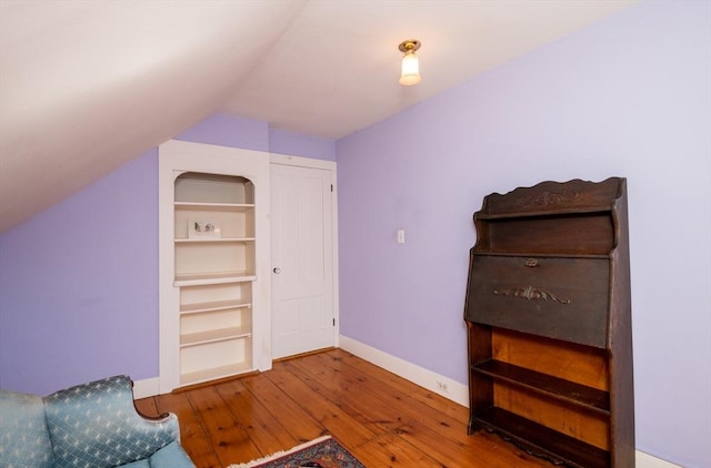 living area with vaulted ceiling, baseboards, and hardwood / wood-style floors
