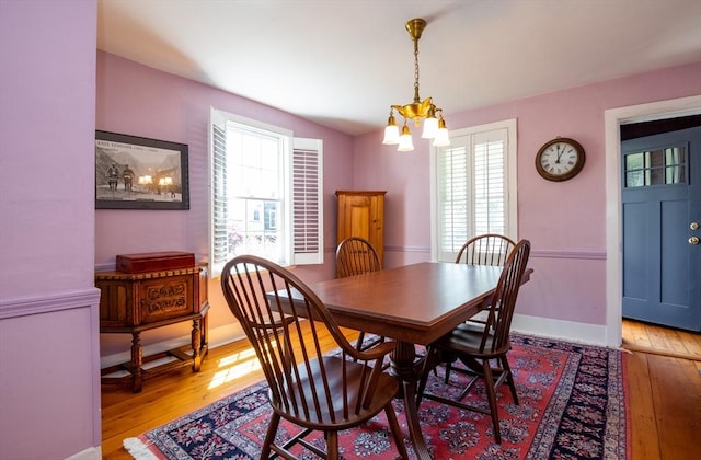 dining area with light wood finished floors, a notable chandelier, and a healthy amount of sunlight