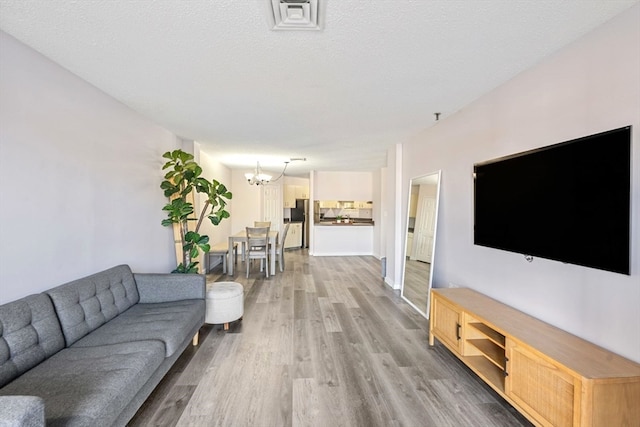 living room featuring a notable chandelier, a textured ceiling, hardwood / wood-style flooring, and sink