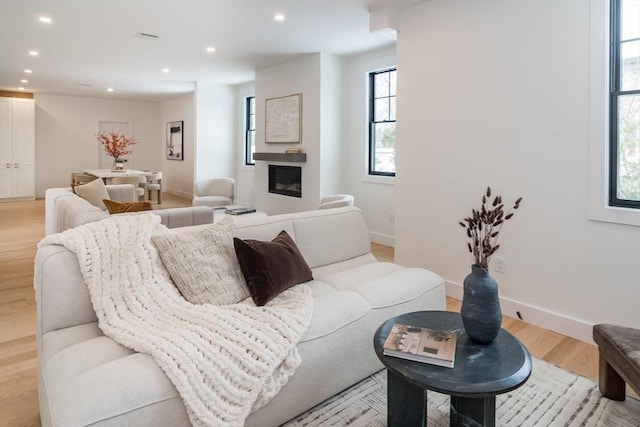 living area featuring baseboards, a fireplace, light wood-style flooring, and recessed lighting