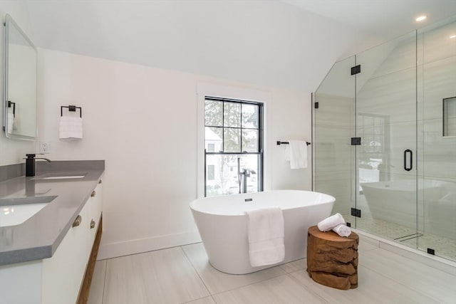 bathroom featuring a sink, vaulted ceiling, a soaking tub, double vanity, and a stall shower