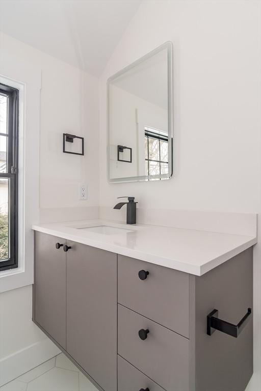 bathroom featuring lofted ceiling, a healthy amount of sunlight, vanity, and baseboards