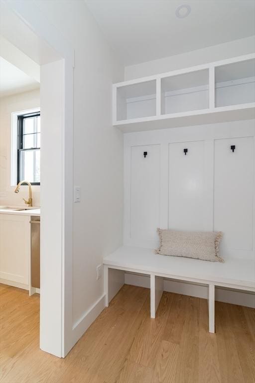 mudroom with light wood-style flooring, baseboards, and a sink