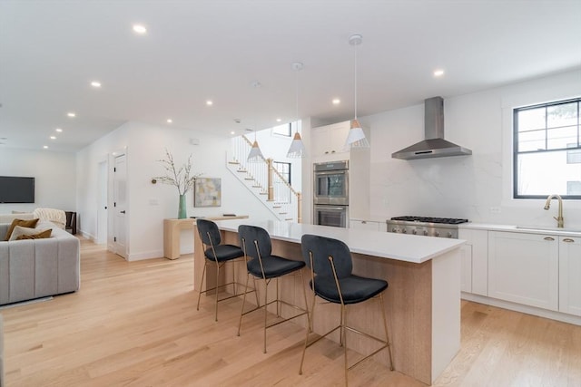 kitchen with wall chimney range hood, a kitchen island, and white cabinetry