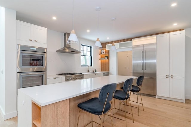 kitchen featuring a kitchen island, white cabinetry, light countertops, wall chimney range hood, and open shelves