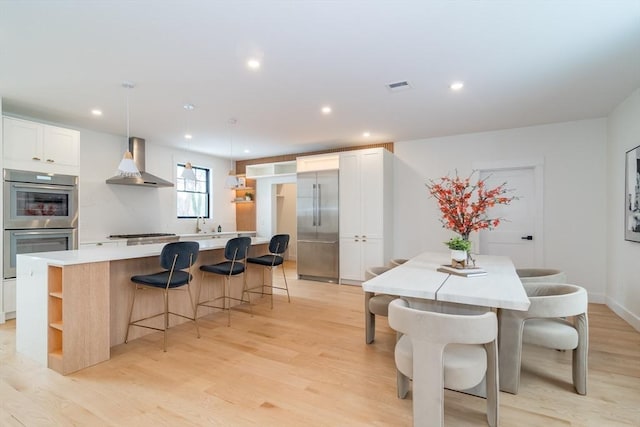 dining area with light wood finished floors, baseboards, visible vents, and recessed lighting