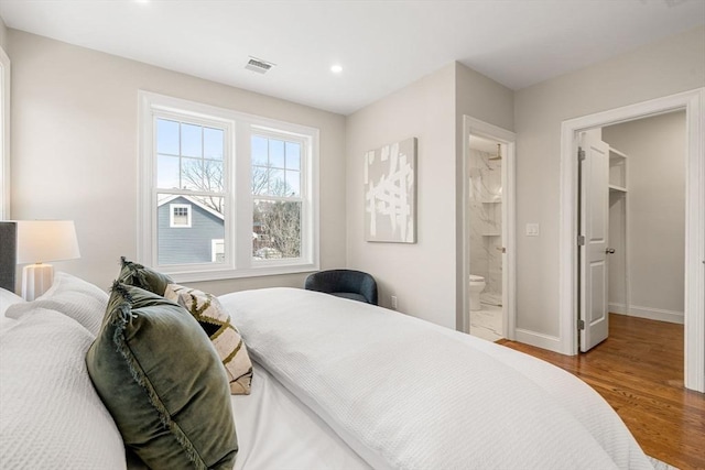 bedroom featuring a spacious closet, wood-type flooring, ensuite bath, and a closet