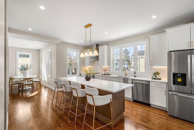 kitchen featuring white cabinetry, hanging light fixtures, stainless steel appliances, and a kitchen island