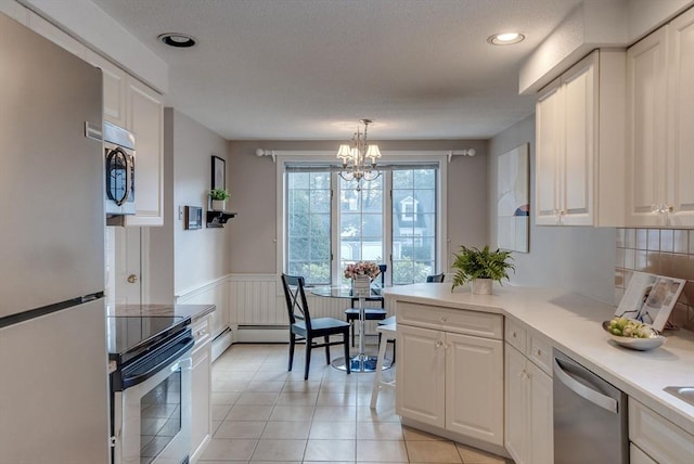 kitchen featuring a wainscoted wall, stainless steel appliances, light countertops, and white cabinets