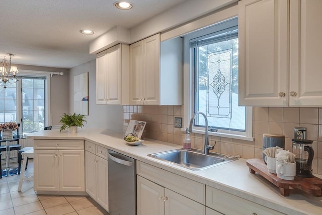 kitchen featuring light countertops, a sink, dishwasher, and white cabinetry