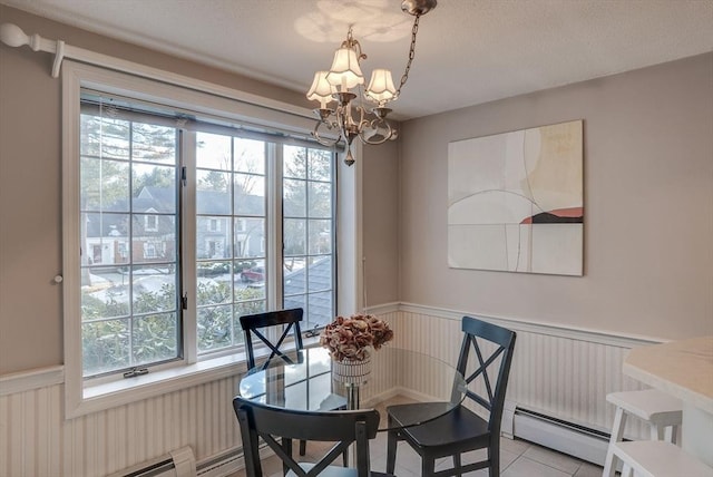 dining space with a baseboard heating unit, wainscoting, a baseboard radiator, and an inviting chandelier