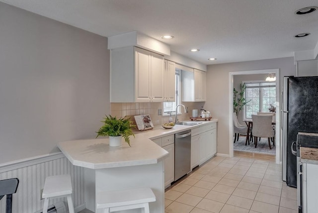 kitchen featuring stainless steel appliances, light countertops, a sink, and white cabinetry