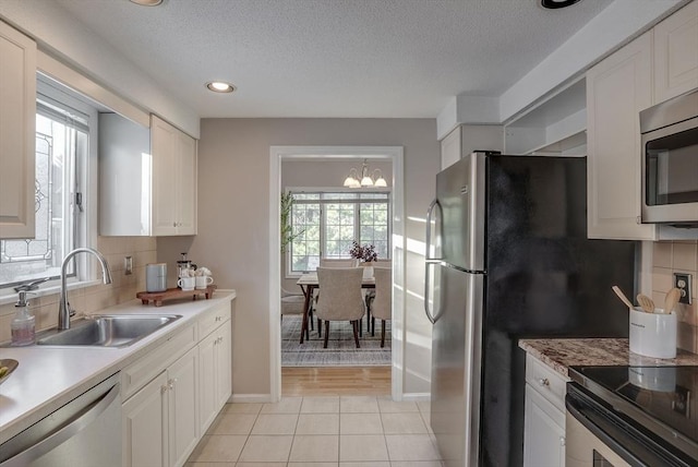 kitchen with light countertops, appliances with stainless steel finishes, a sink, and white cabinetry