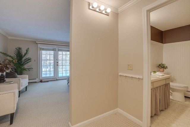 hallway with a baseboard heating unit, baseboards, crown molding, and light colored carpet