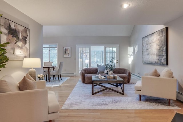 living area with light wood-style floors, a baseboard heating unit, and vaulted ceiling