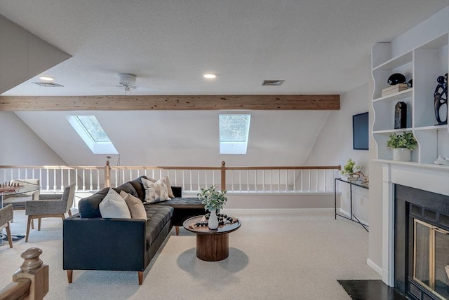 living area with visible vents, a fireplace with flush hearth, lofted ceiling with skylight, carpet flooring, and baseboards