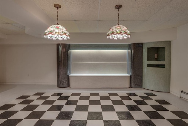 unfurnished dining area featuring a drop ceiling, baseboards, and tile patterned floors