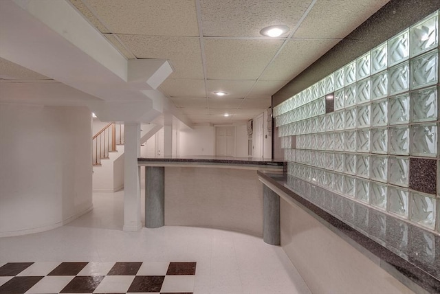 bar with stairs, a paneled ceiling, baseboards, and tile patterned floors