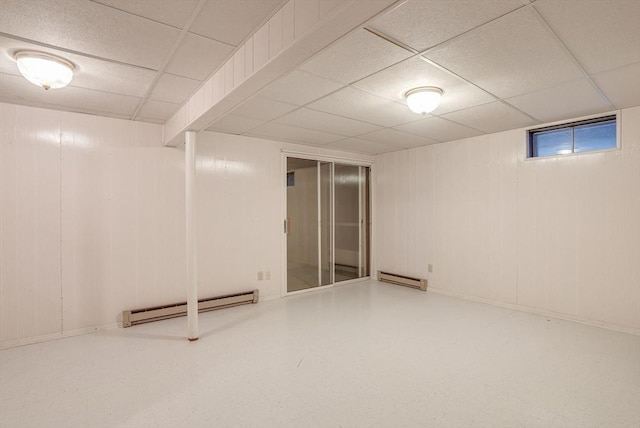 finished basement featuring a drop ceiling, a baseboard radiator, and tile patterned floors