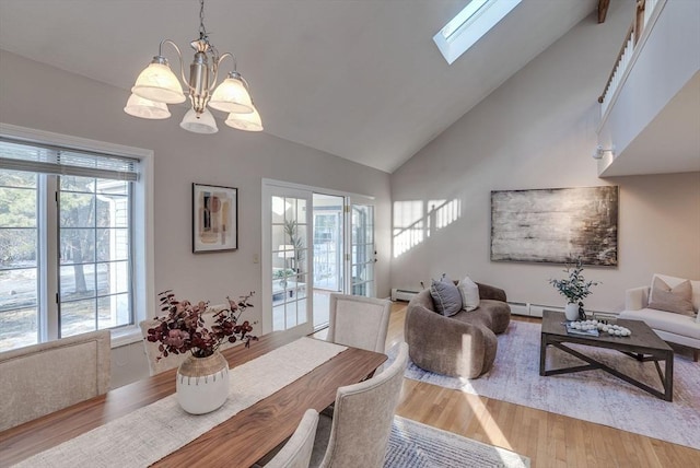 dining area featuring a skylight, a chandelier, wood finished floors, baseboard heating, and high vaulted ceiling