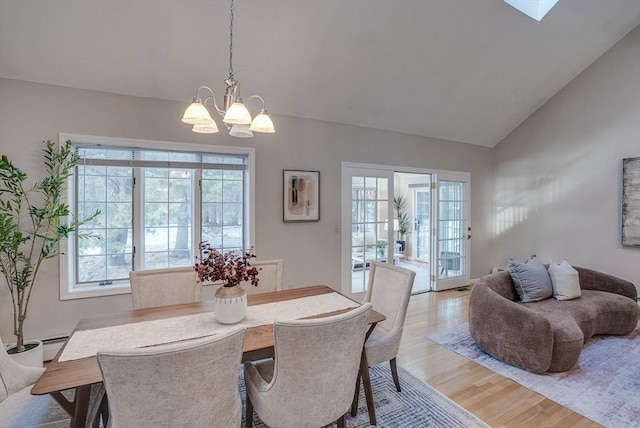 dining room with a chandelier, lofted ceiling, and light wood finished floors